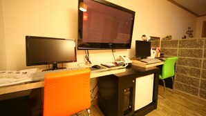 A hotel room with a desk, two monitors, a keyboard, a mouse, a telephone, and a green chair. - Chuncheon Myeongdong Hotel (Chuncheon)