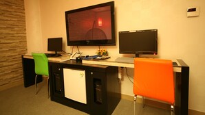 A conference room with a large flat-screen TV, two monitors, a small refrigerator, and two chairs. - Chuncheon Myeongdong Hotel (Chuncheon)