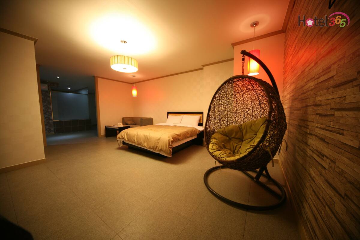 Una habitación de hotel moderna con una cama, un sillón colgante y vistas a un balcón.