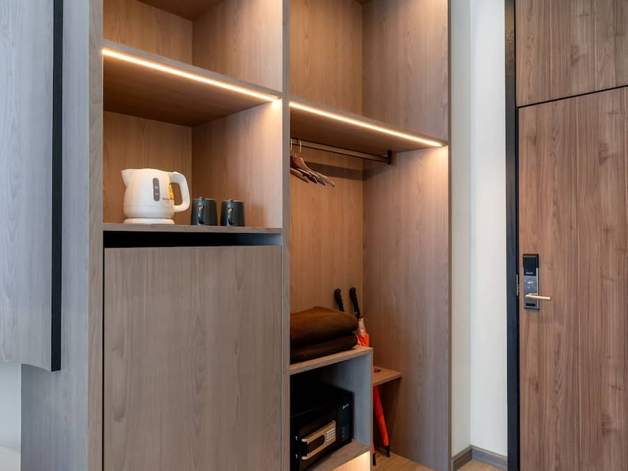 A modern closet with wooden shelves, a hanging rod, and a built-in microwave.