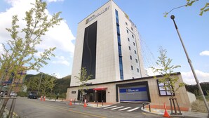 Un hotel llamado 'Innova Valley' con un diseño moderno, un garaje de estacionamiento y cielo despejado.
