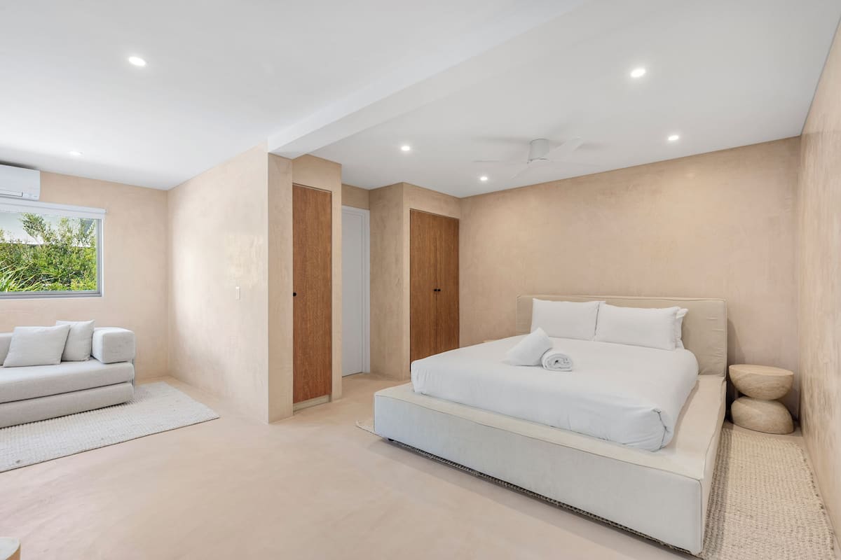 Ein modernes Schlafzimmer mit einem großen Bett, einer Couch und einem begehbaren Kleiderschrank.