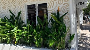 A building with a patterned facade, a sign reading 'TEN,' and a planter with green plants. - Hastings House (Noosa Heads)