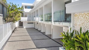 A modern building with a covered walkway, glass doors, and a patterned wall. - Hastings House (Noosa Heads)