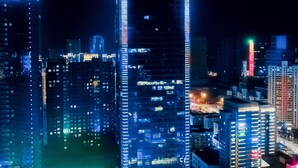 Paisagem urbana noturna com arranha-céus iluminados, rua movimentada e um edifício de destaque com a sinalização 'DASHANG GROUP'.