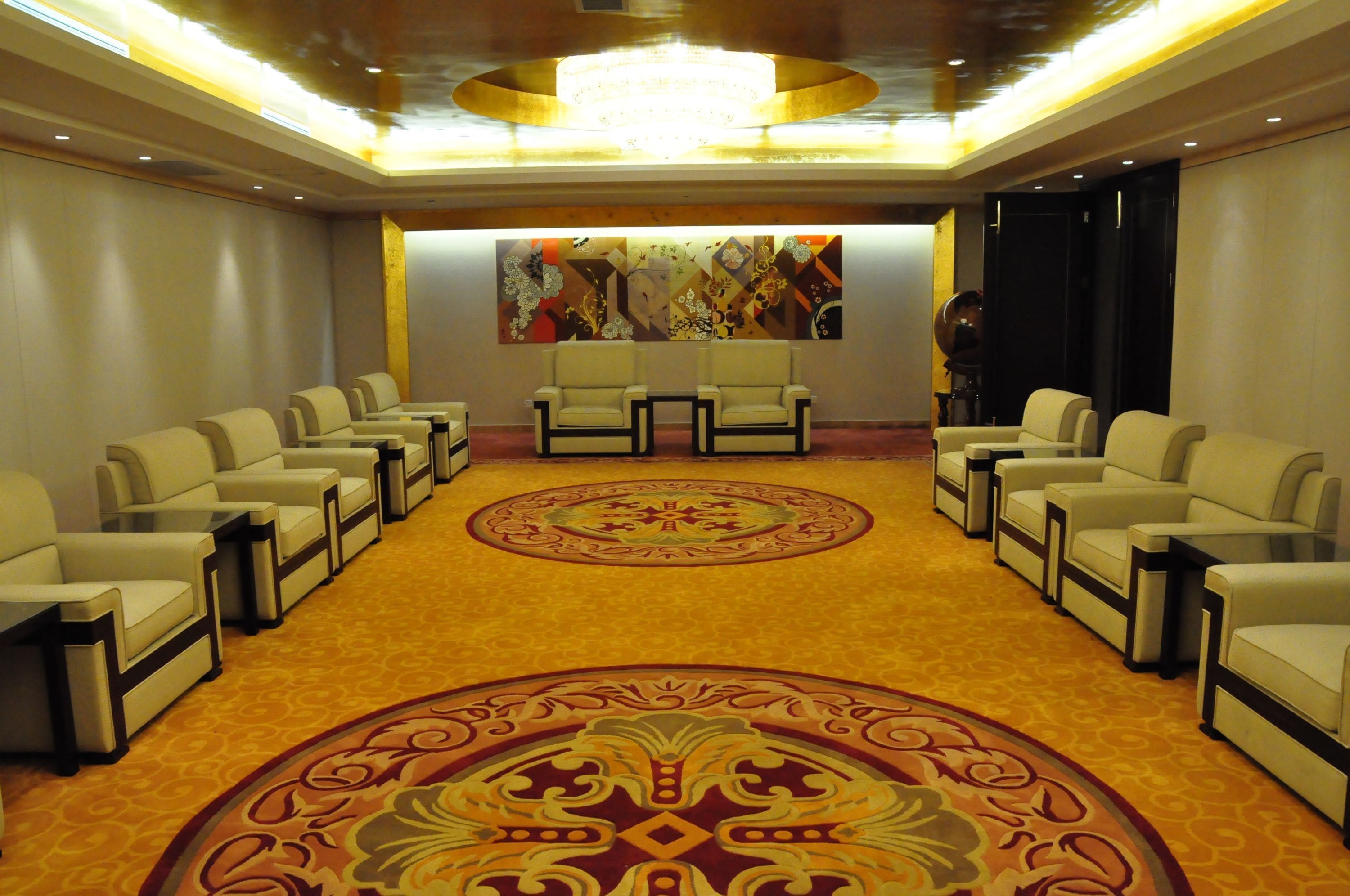 A conference room with a carpeted floor, a large chandelier, and a wall with abstract art.