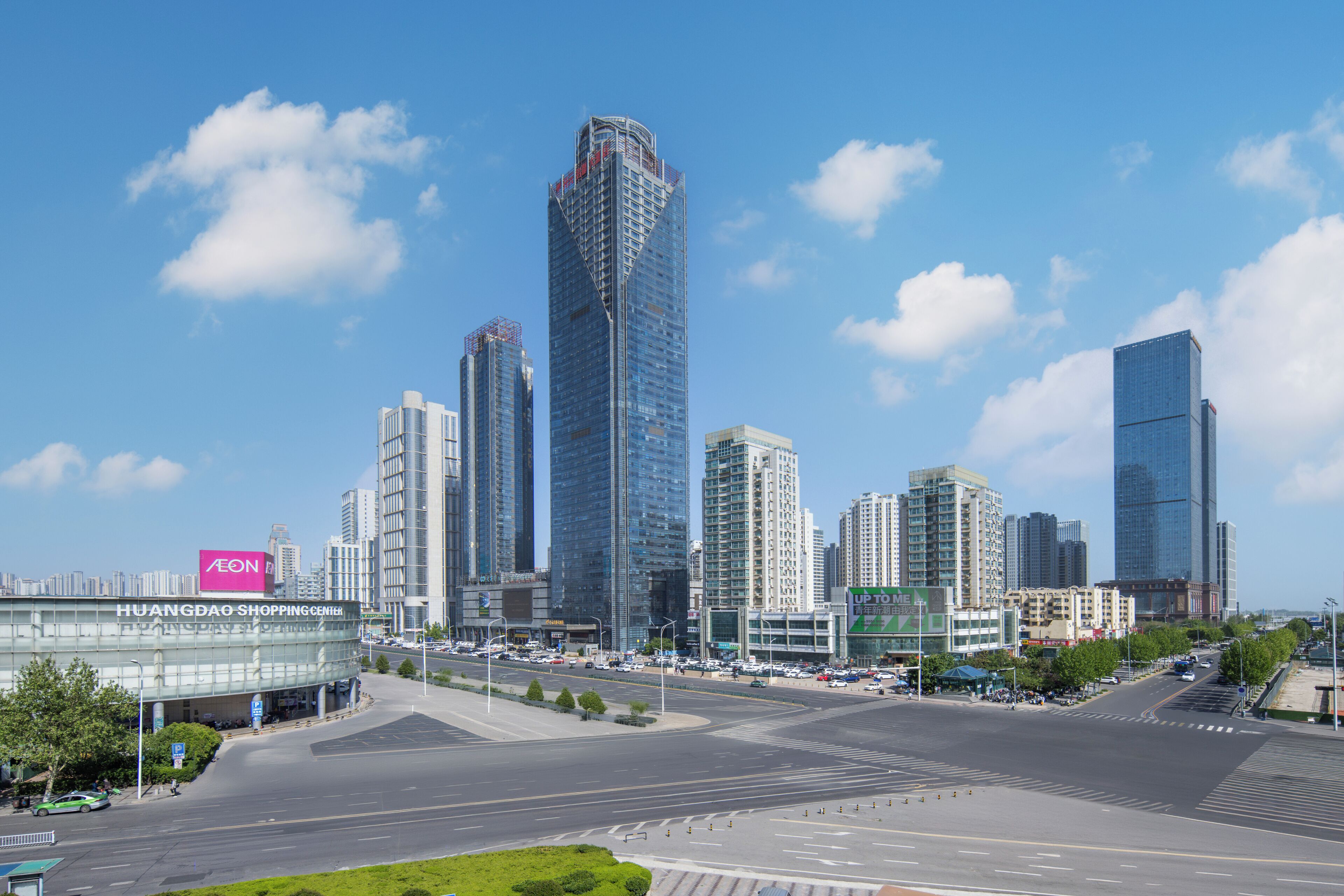 A cityscape with modern high-rise buildings, a shopping center, and a clear sky.