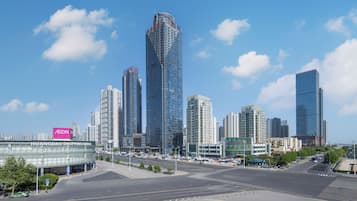 A cityscape with modern high-rise buildings, a shopping center, and a clear sky.