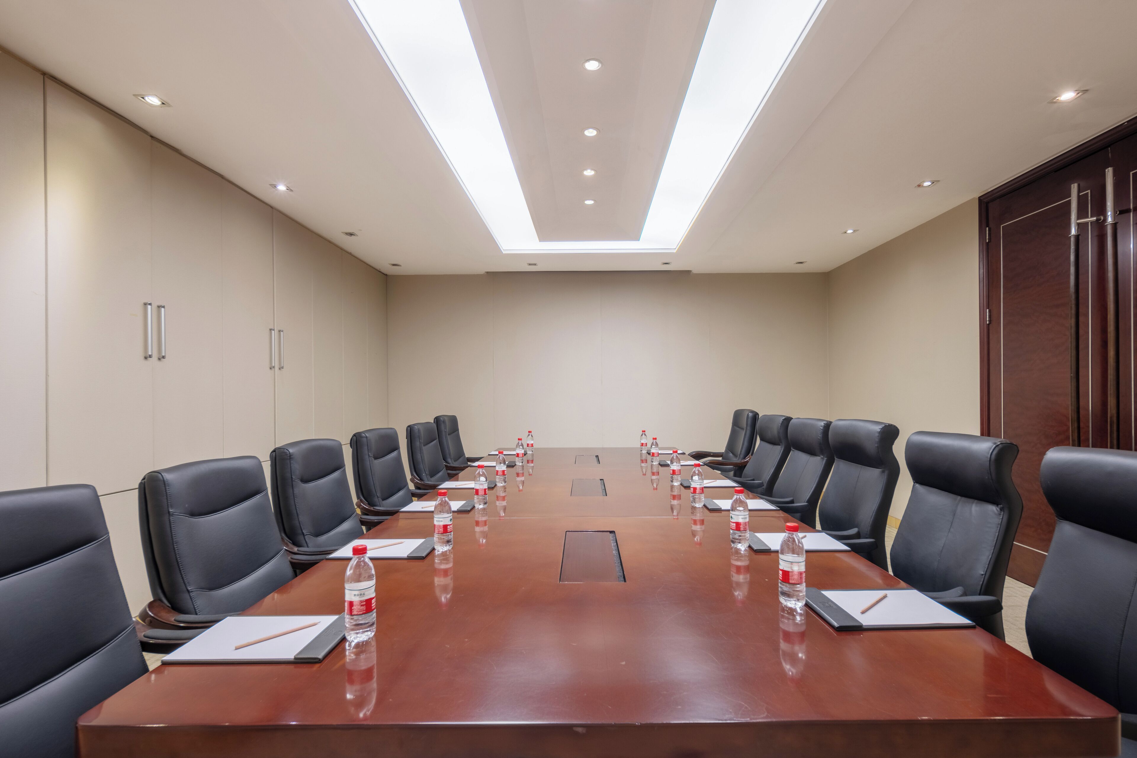 A conference room with a long table, black leather chairs, and water bottles on the table.