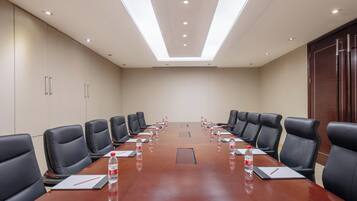 A conference room with a long table, black leather chairs, and water bottles on the table.