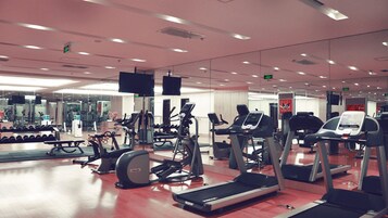 A gym with treadmills, elliptical machines, and free weights.