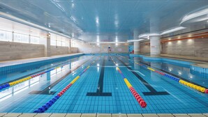 Uma grande piscina interior com várias pistas, água cristalina e paredes revestidas de azulejos.