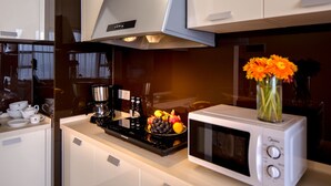 Una cocina moderna con microondas, cafetera y frutero en la encimera.