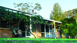 Een huis met een bakstenen gevel, grote ramen en een overdekte veranda.