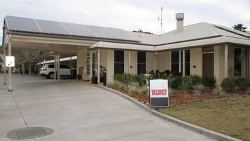 Un edificio con un cartel de 'VACANCY', paneles solares y una zona de estacionamiento techada.