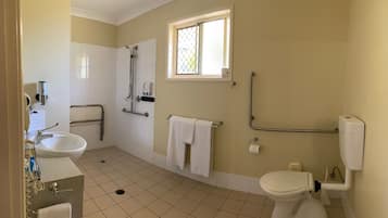 Un bagno con lavandino, toilette e doccia. Una finestra permette l'ingresso di luce naturale, ed è presente una maniglia per facilitare l'accesso.