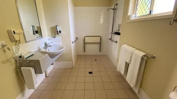 A bathroom with a sink, mirror, towel rack, and a shower area.