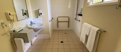 Een badkamer met een wastafel, spiegel, handdoekhouder en douche.