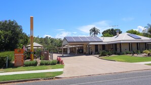 A building with a covered entrance, solar panels on the roof, and a signboard with amenities. - Country Roads Motor Inn Gayndah Qld (Gayndah)