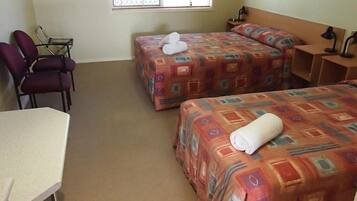 A hotel room with two beds, a desk, and a chair.