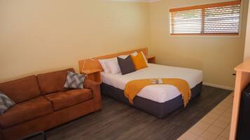 Un dormitorio con cama, sofá y ventana con persianas.