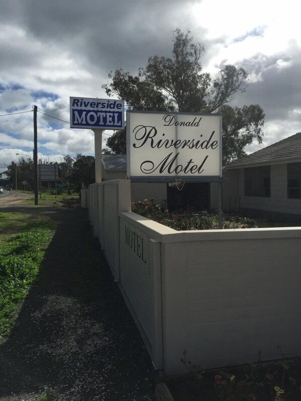 A motel sign with the name 'Riverside Motel' and a smaller sign above it reading 'Riverside Motel'.