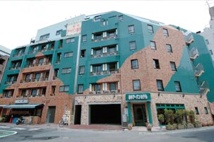 Un edificio de varios pisos con fachadas de ladrillo y color turquesa, que cuenta con una entrada a nivel de calle y una señal.