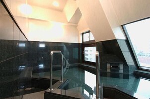 Un interior moderno con suelo de cristal, barandillas metálicas y vistas de la ciudad a través de un ventanal amplio.