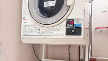 A front-loading washing machine with a control panel and a detergent dispenser below it.