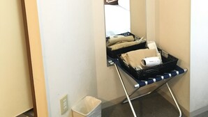 A hotel room with a large mirror, a wooden hanger, a black luggage trolley, and a white trash bin. - Urban Hotel Tokyo Fuchu-Higashiguchi (Fuchu)