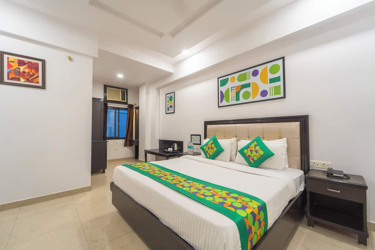 A hotel room with a large bed, a bedside table, a nightstand, and a window.