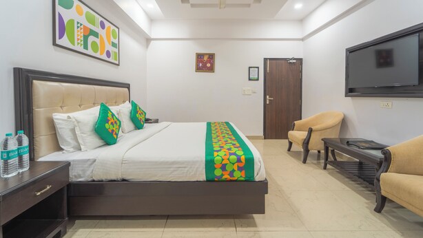 A hotel room with a bed, a chair, a TV, and a ceiling fan.
