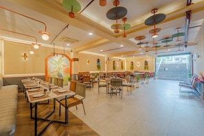 A spacious restaurant with multiple dining areas, a staircase leading to an outdoor area, and a variety of seating options including tables and chairs. - Treebo Shivam Inn Near Singapore Mall (Lucknow)