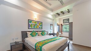 A modern hotel room with a large bed, bedside tables, a desk, and a window with a view of trees. - Treebo Shivam Inn Near Singapore Mall (Lucknow)