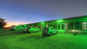 A building with multiple parking spaces and a green-lit exterior. - Matilda Motel (Winton)
