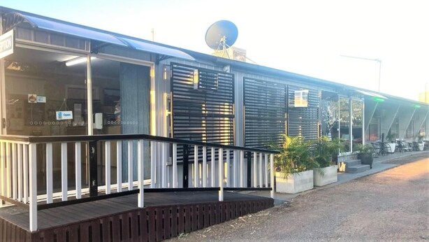A modern building with a glass facade, a satellite dish, and a wooden deck. - Matilda Motel (Winton)