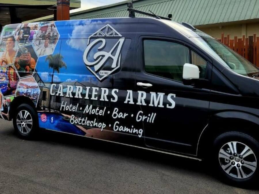 Una camioneta negra con la marca 'CARRIERS ARMS' que indica hotel, motel, bar, parrilla, Bottlestead y juegos.