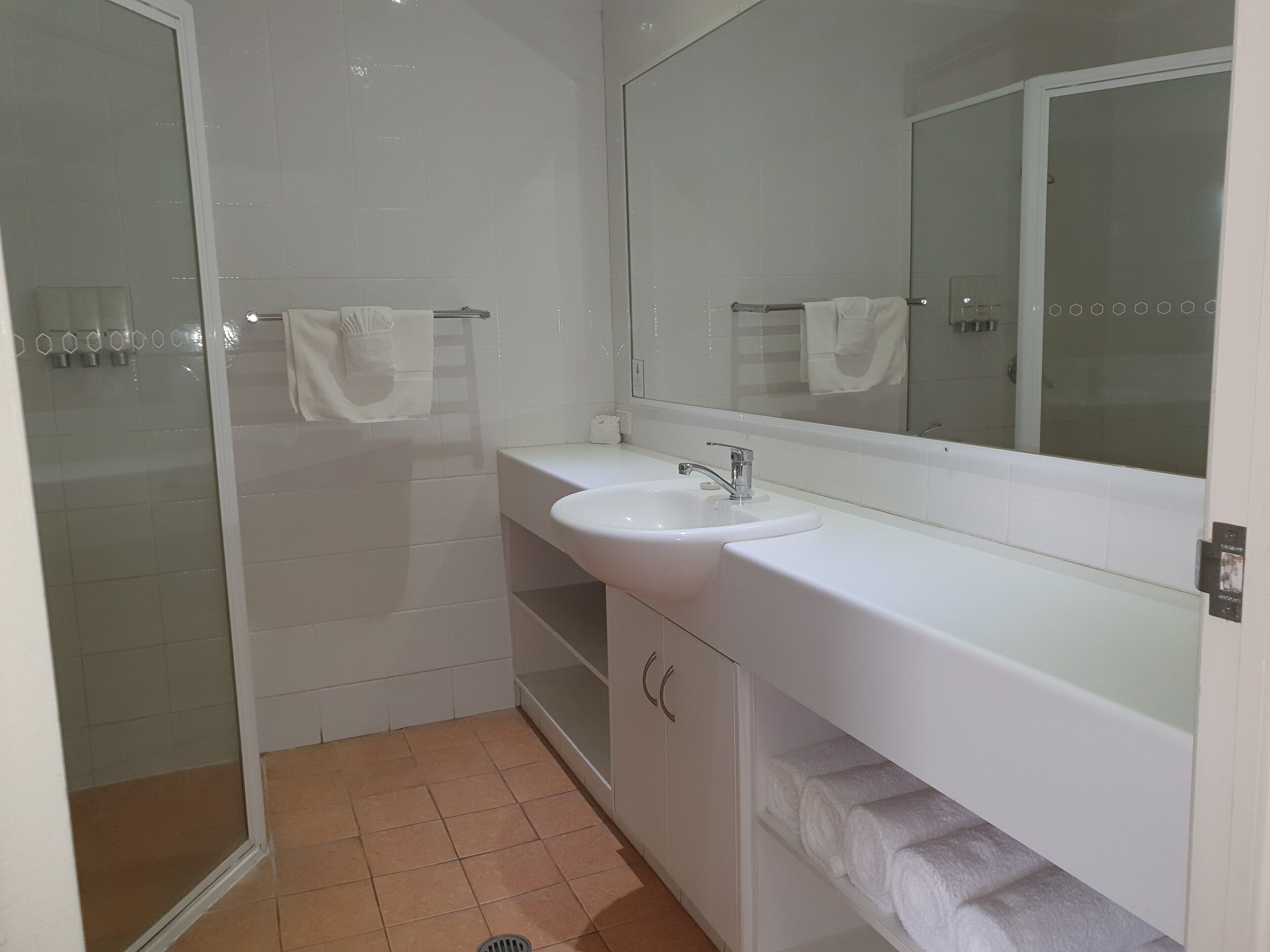 Un baño con lavamanos blanco, un espejo y una zona de ducha.