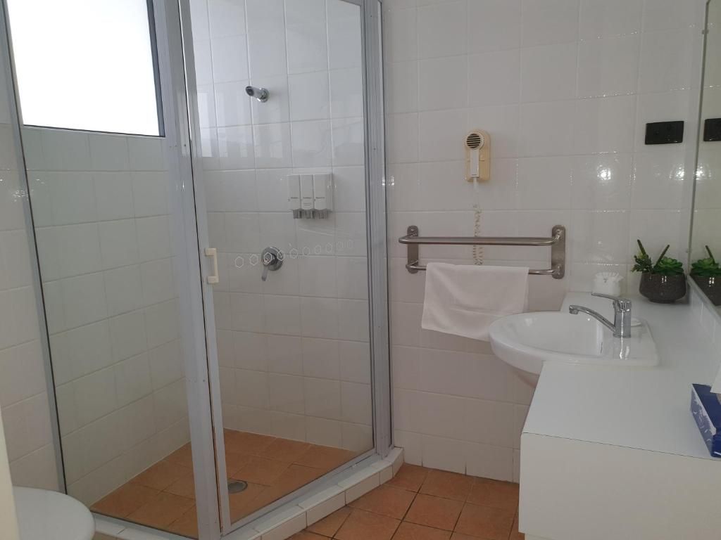 Un bagno con doccia vetrata, lavandino bianco e porta asciugamani.