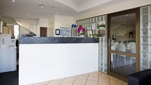 A reception area with a marble counter, glass doors leading to a dining area, and a staircase in the background. - Carriers Arms Hotel (Maryborough)