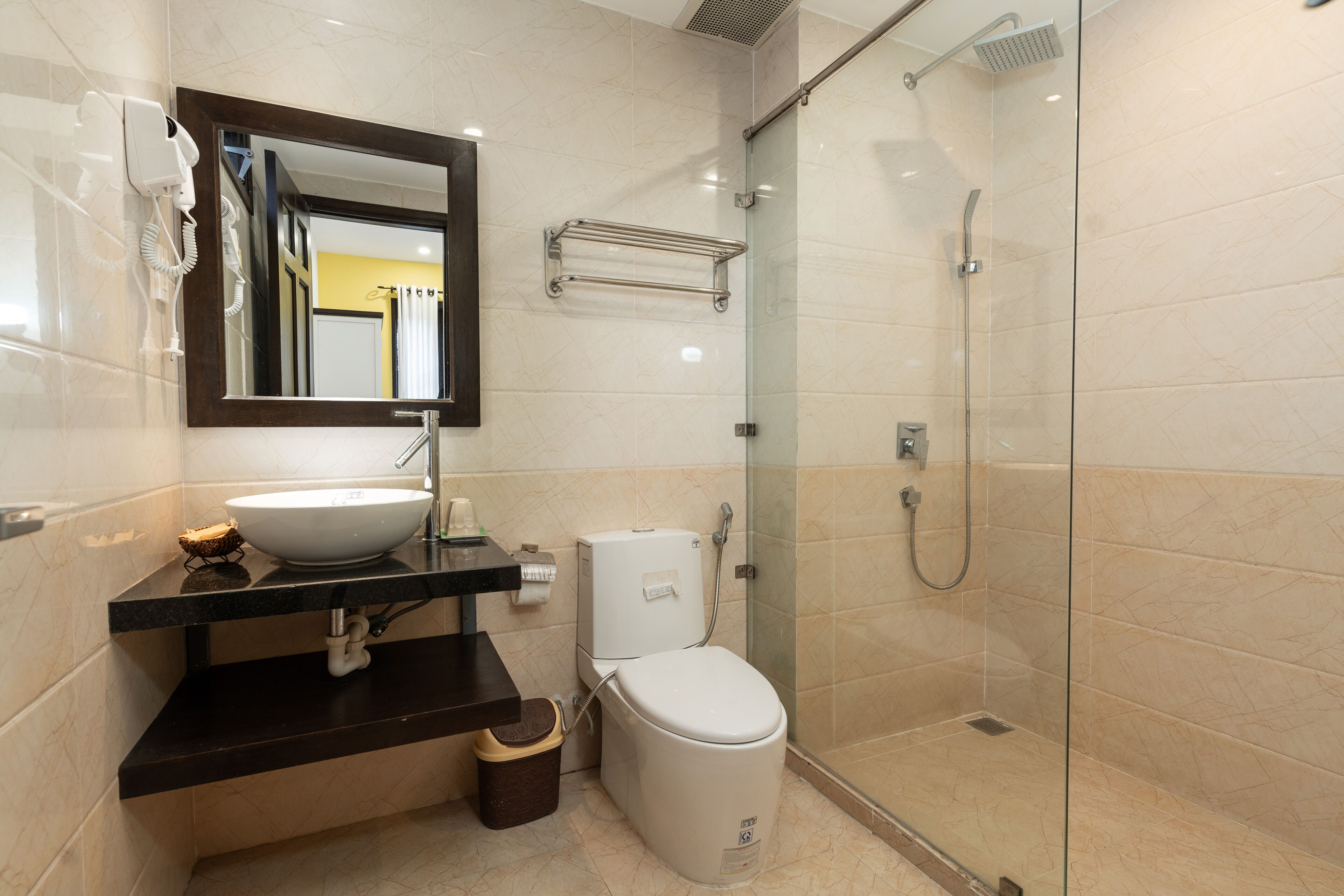 Une salle de bain moderne avec une douche à parois de verre, des toilettes blanches et un lavabo avec un miroir au-dessus.