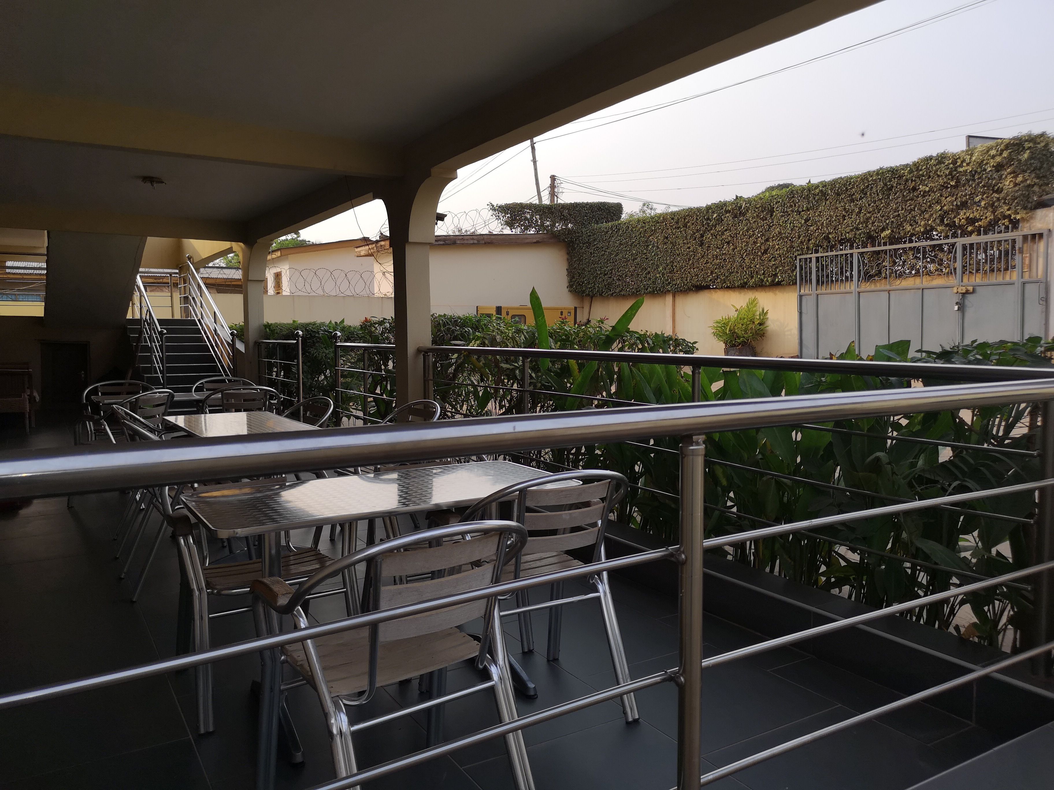 Una terraza exterior con barandillas de metal, mesas y sillas.