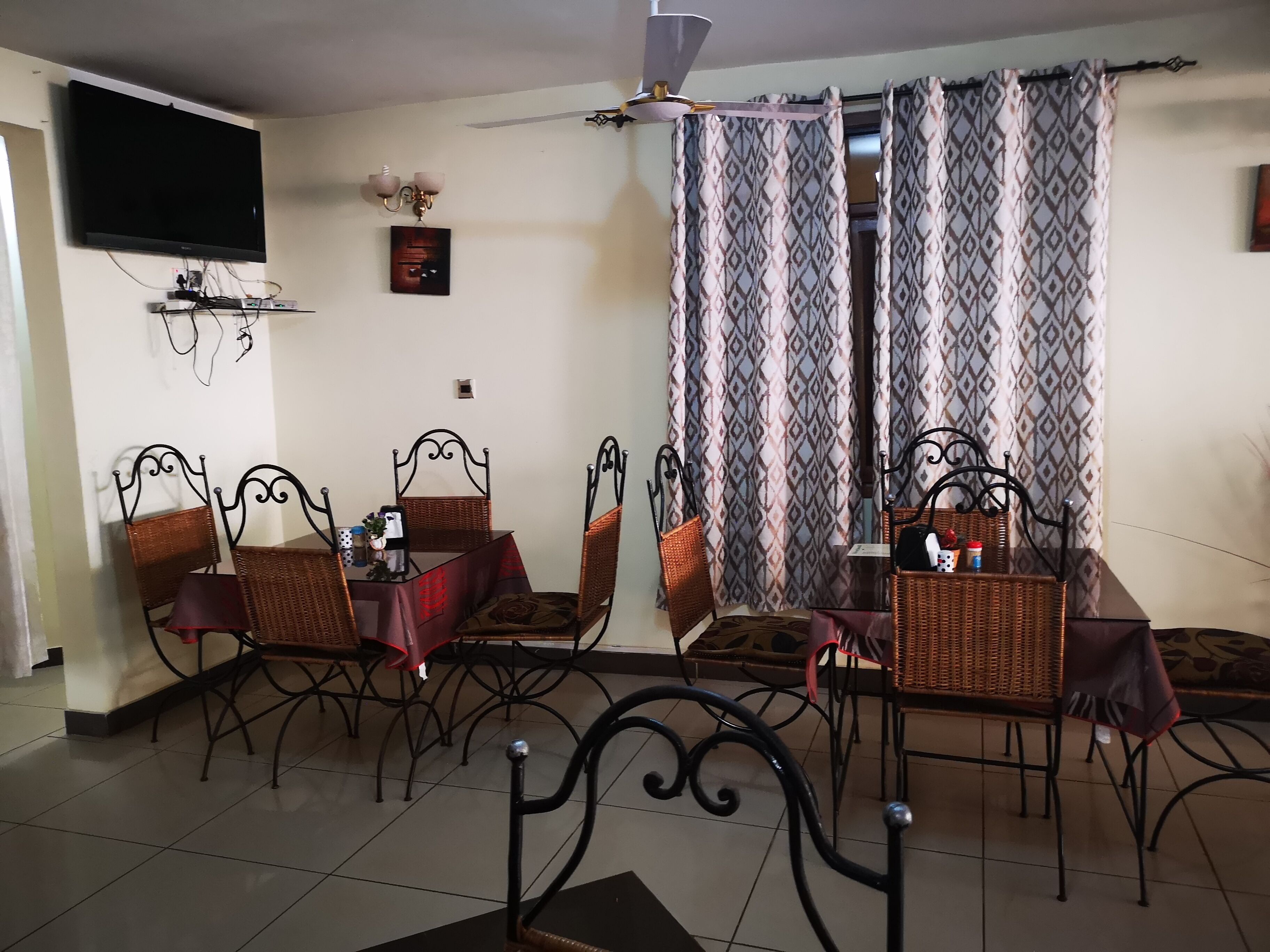 A dining area with a table and chairs, a ceiling fan, and patterned curtains.