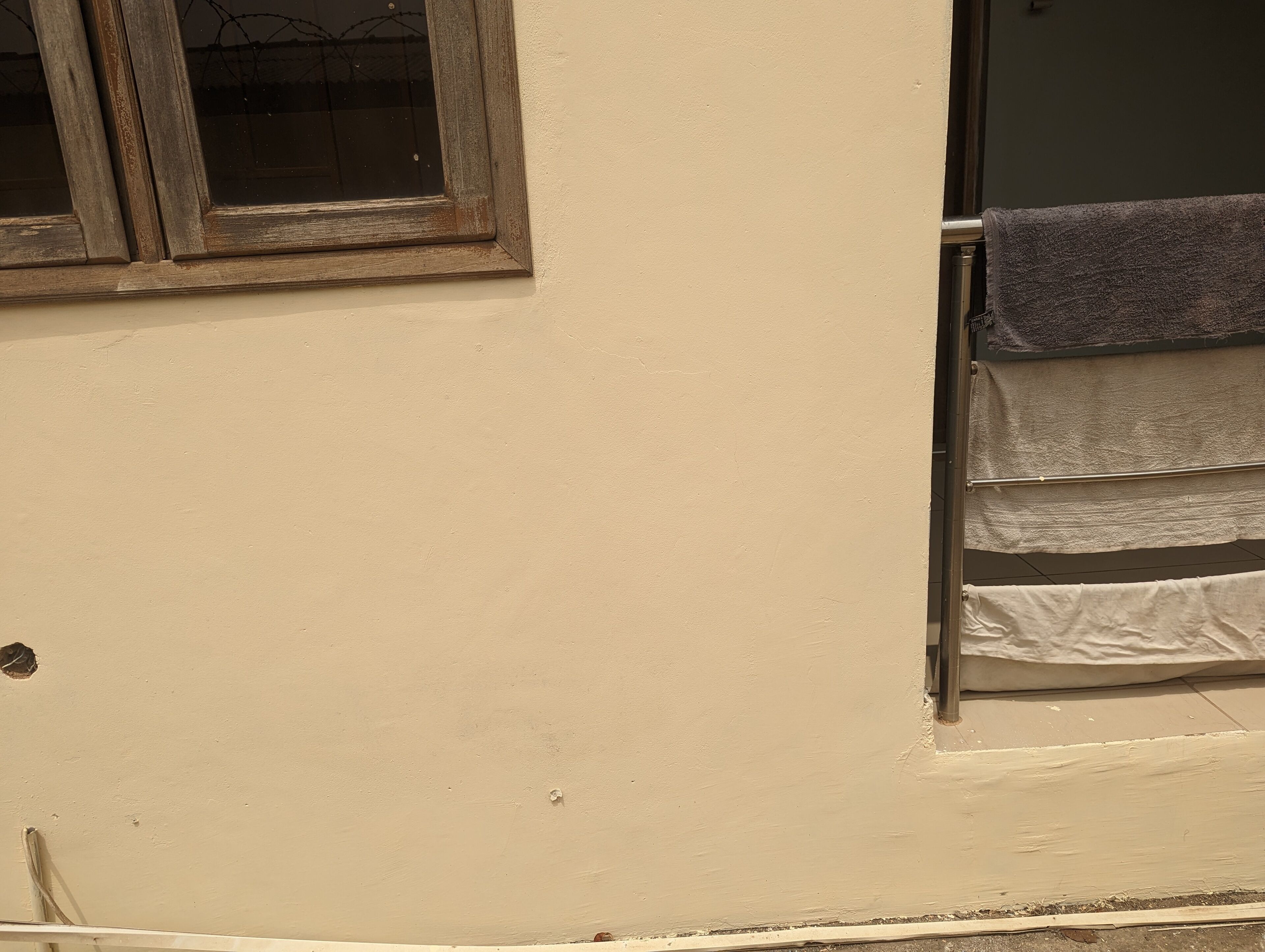 A beige wall with a window and a towel rack.