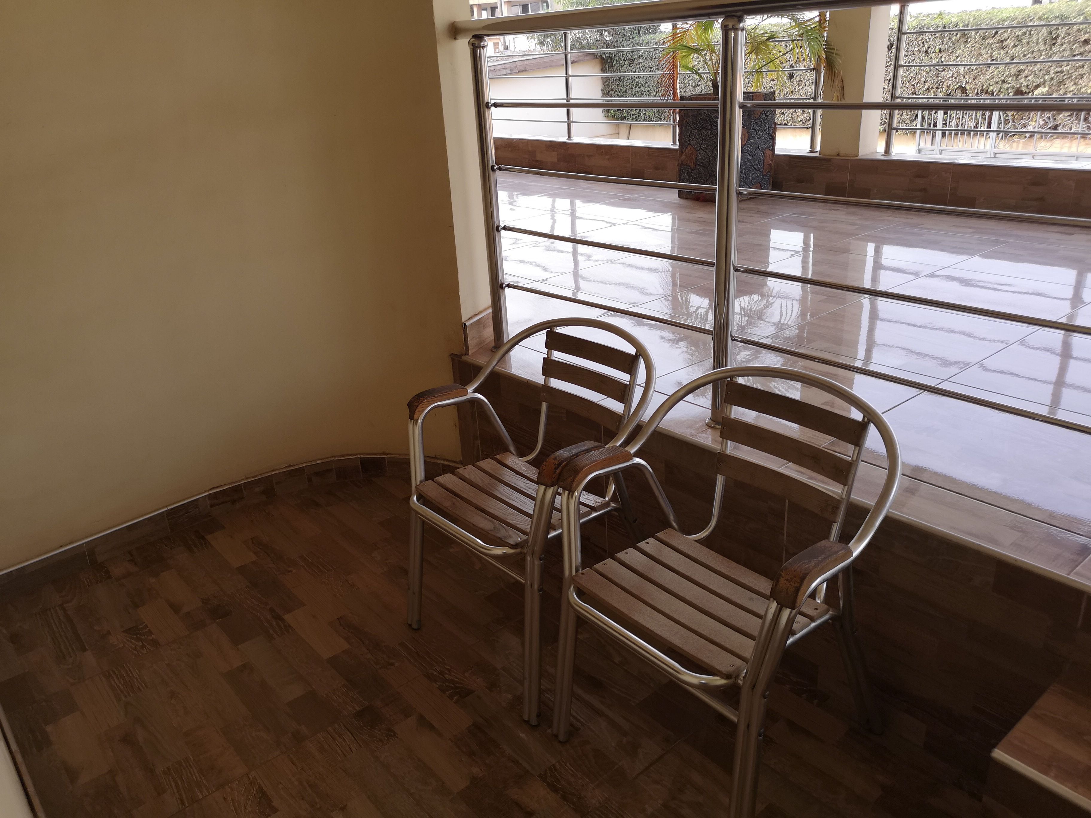 A corner of a room with two metal chairs and a wooden floor.