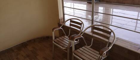 A corner of a room with two metal chairs and a wooden floor.