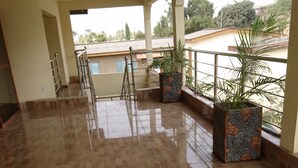 A spacious indoor area with a tiled floor, a staircase, and potted plants.