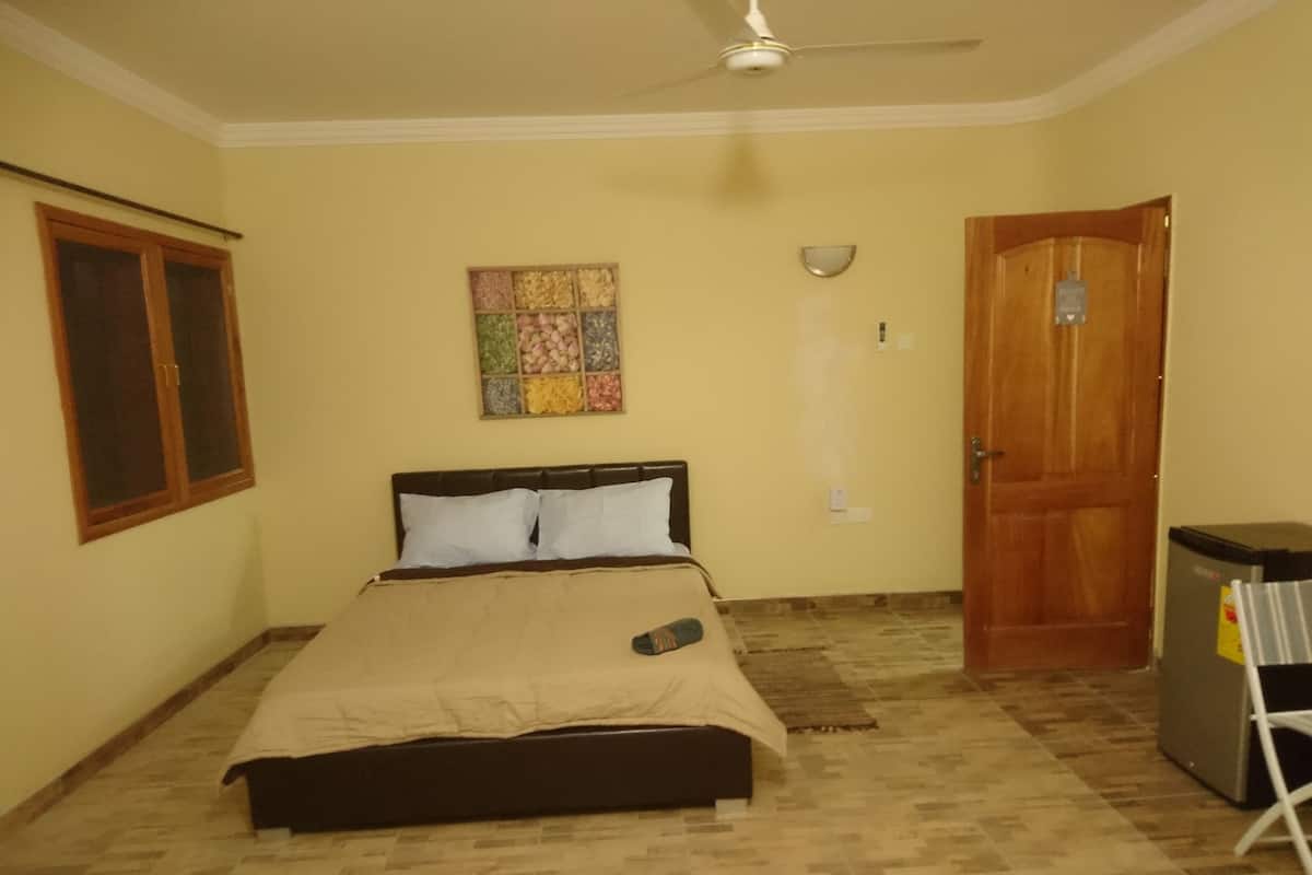 Ein Schlafzimmer mit Bett, Deckenventilator, Tür und einer wandmontierten Lampe.