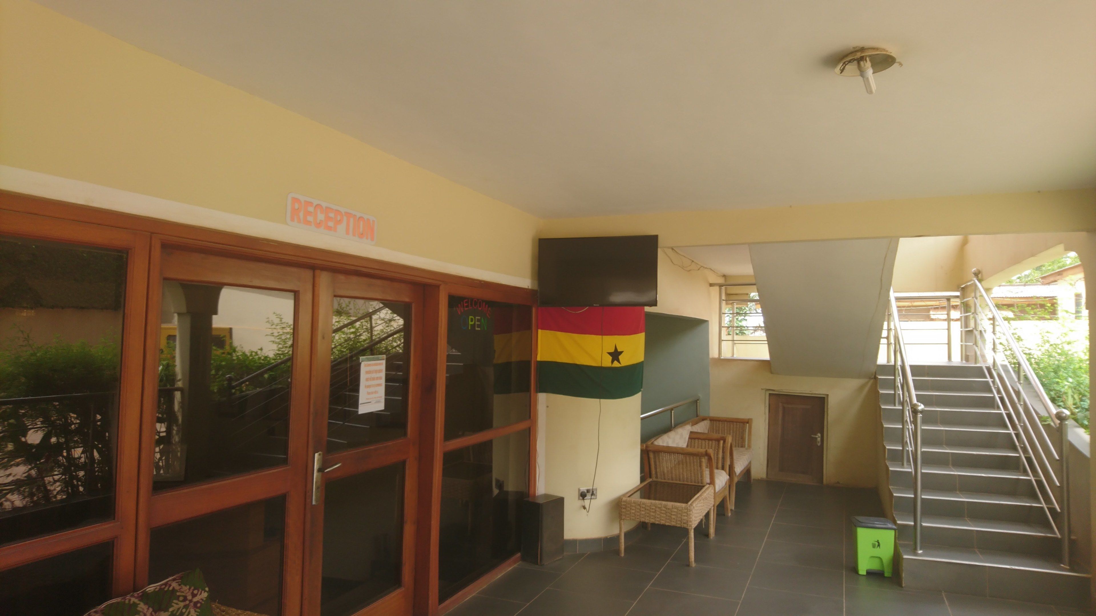 Un área de recepción con un letrero, una escalera y una bandera.