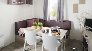 A compact living space with a dining area, a sofa, and a television. - Batuca Village & Camping (Terme Vigliatore)